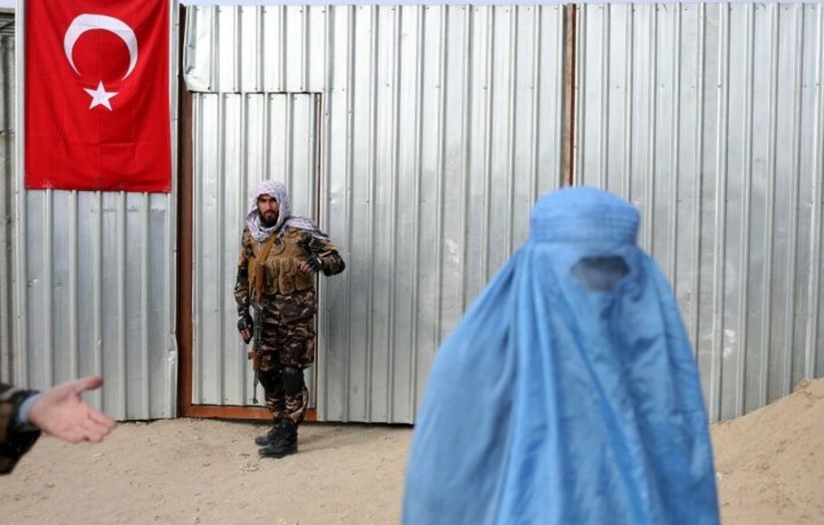 Seorang pasukan Taliban terlihat saat perempuan Afghanistan hendakmenerima paket bantuan yang dibagikan oleh kelompok bantuan kemanusiaan asal Turki di pusat distribusi di Kabul, Afganistan.