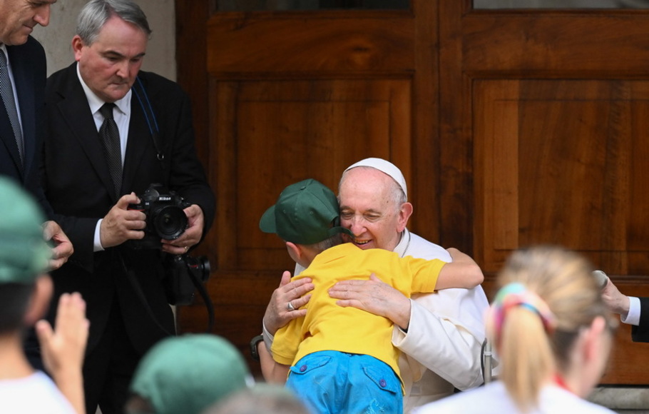 Paus Fransiskus memeluk seorang anak pengungsi dari Ukraina saat ia memimpin pertemuan 