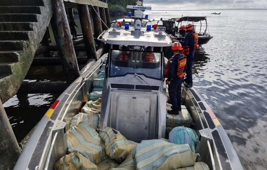 Anggota personel Angkatan Laut Kolombia berdiri di samping paket 600 kilogram kokain dan 1,7 ton mariyuana yang disita di atas kapal di Buenaventura, Valle del Cauca, Kolombia, pada Jumat 3 Juni 2022. 