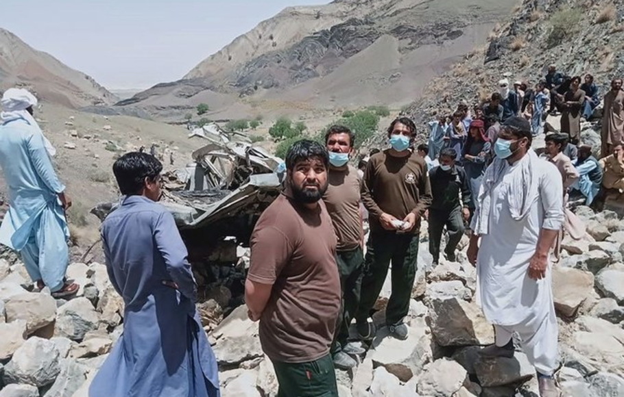 Penonton dan penyelamat berkumpul di sekitar reruntuhan bus penumpang yang jatuh ke jurang yang dalam di distrik Qila Saifullah di provinsi Balochistan, Pakistan pada 8 Juni 2022. 