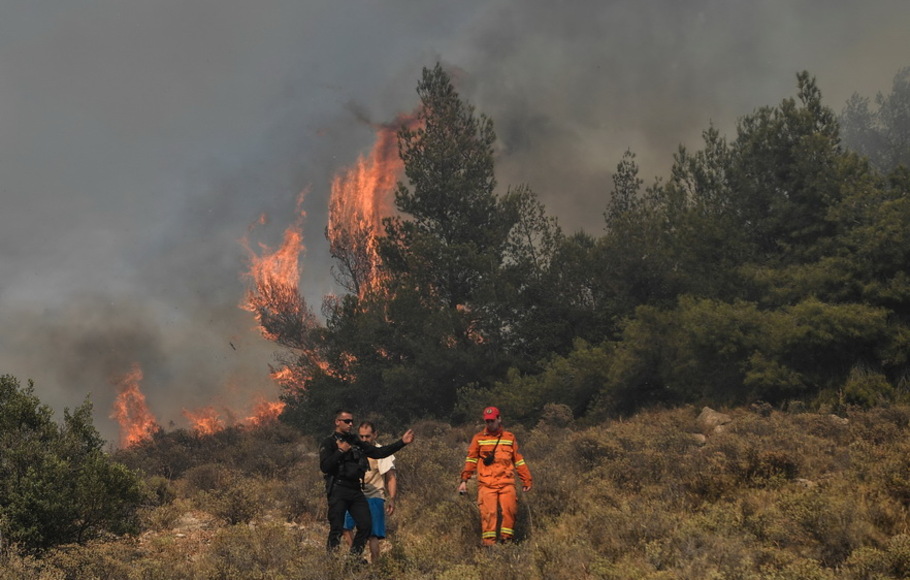 Kebakaran hutan membakar dekat rumah-rumah di daerah Panorama Voulas, selatan Athena, Yunani pada Sabtu 4 Juni 2022. Kebakaran hutan memaksa warga mengungsi
