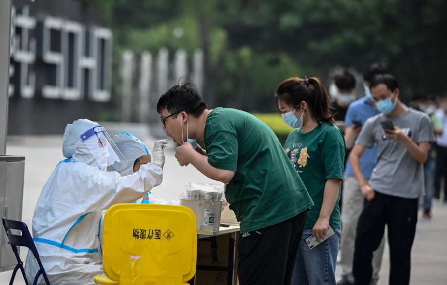 Seorang petugas kesehatan mengambil sampel swab dari seorang pria untuk diuji virus corona Covid-19 di stasiun pengujian asam nukleat di Beijing, Tiongkok pada Jumat 10 Juni 2022.