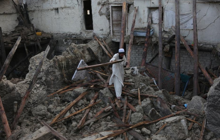 Seorang pria berdiri di atas puing-puing sebuah rumah yang rusak akibat gempa bumi di provinsi Paktika, Afghanistan, pada Kamis 23 Juni 2022. Pemerintahan Taliban di Afghanistan telah meminta bantuan internasional di tengah operasi penyelamatan 