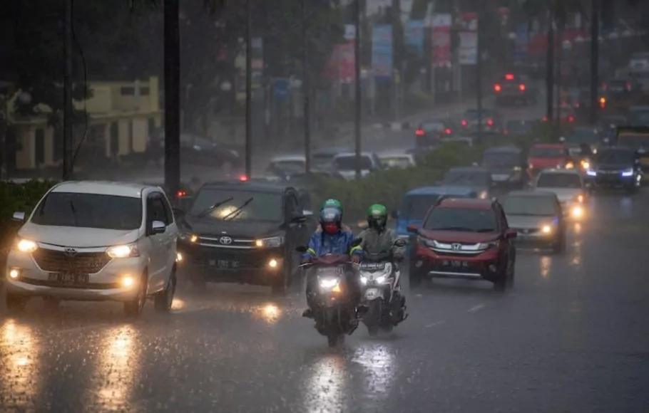 Pengendara menerobos hujan lebat saat melintas di jalan protokol Palembang, Sumatera Selatan.