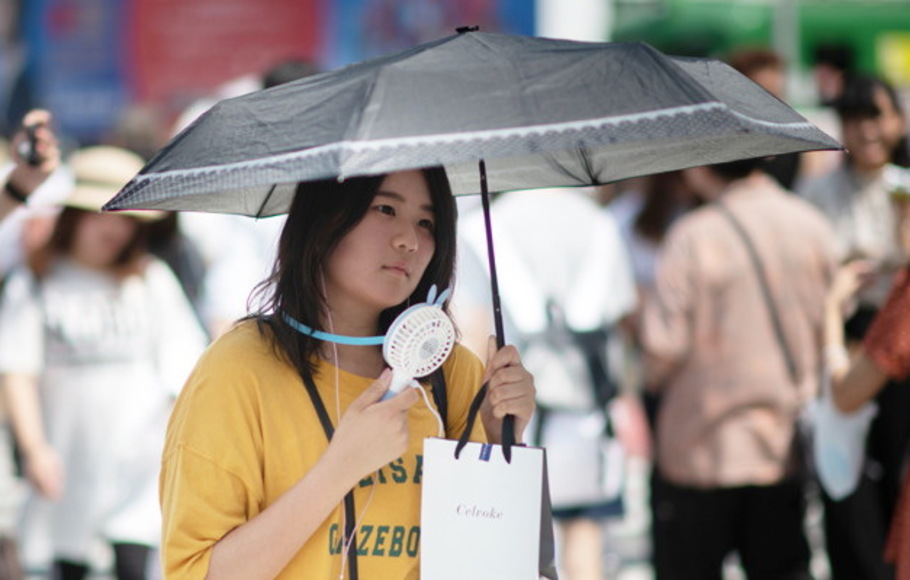 Seorang wanita menggunakan kipas angin portabel untuk mendinginkan dirinya di Tokyo, Jepang pada 24 Juli 2018, saat Jepang mengalami gelombang panas. 