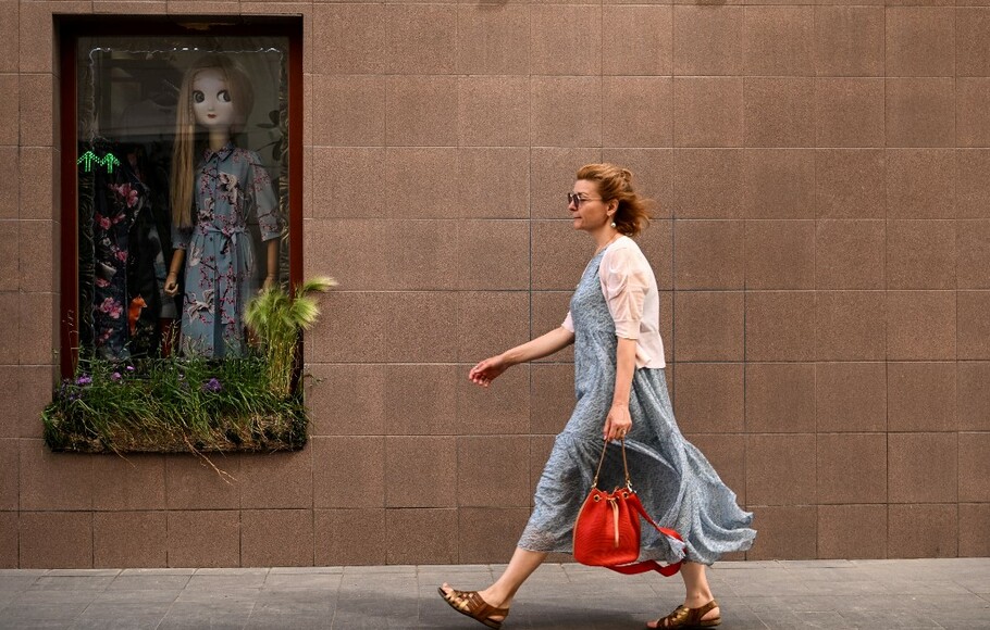 Seorang wanita berjalan melewati toko pakaian di pusat kota Moskwa, Rusia pada 29 Juni 2022.