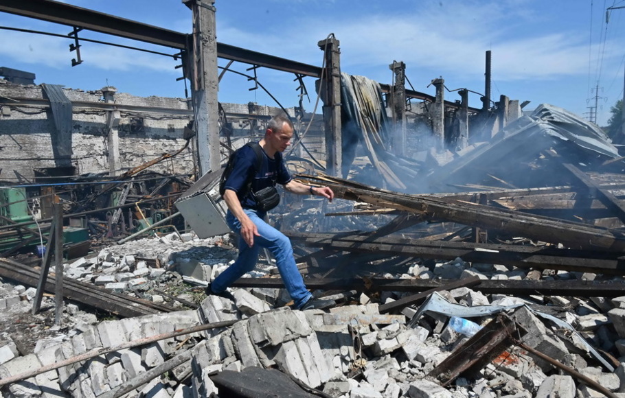 Seorang pria berjalan melalui puing-puing bangunan yang hancur di pabrik Mashgidroprivod, setelah serangan rudal Rusia di Kharkiv pada Rabu 29 Juni 2022 di tengah invasi Rusia ke Ukraina. 