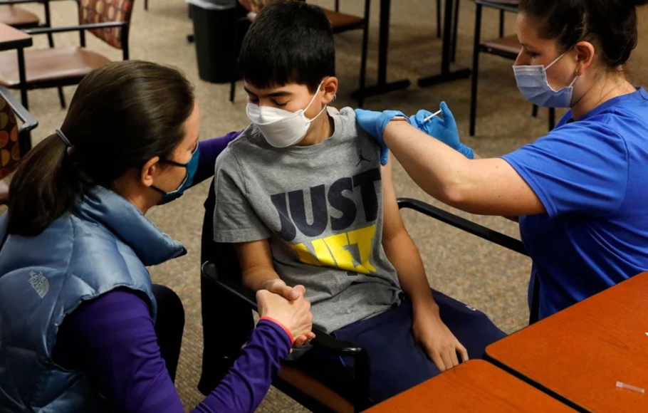 Seorang anak ditemani obunya saat menerima vaksinasi Covid-19 di Bloomfield Hills, Michigan, AS