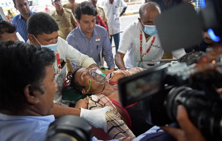 Seorang pria dipindahkan dengan tandu saat tiba dengan ambulans di rumah sakit sipil di Ahmedabad, India pada Selasa 26 Juli 2022, setelah menderita masalah kesehatan karena mengonsumsi minuman keras oplosan.
