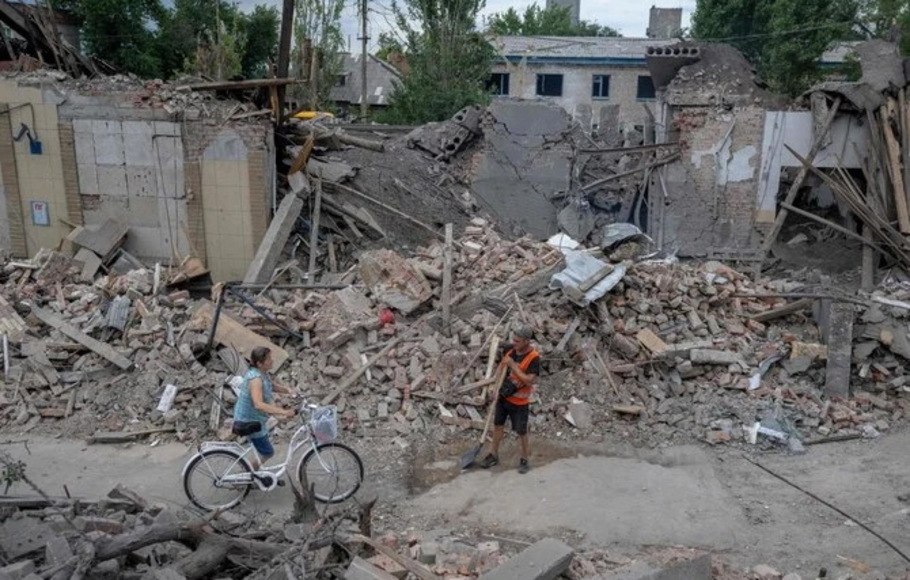 Seorang penduduk setempat mendorong sepedanya melalui bangunan yang rusak di Toretsk, Ukraina timur, pada 5 Agustus 2022, di tengah invasi Rusia ke Ukraina.