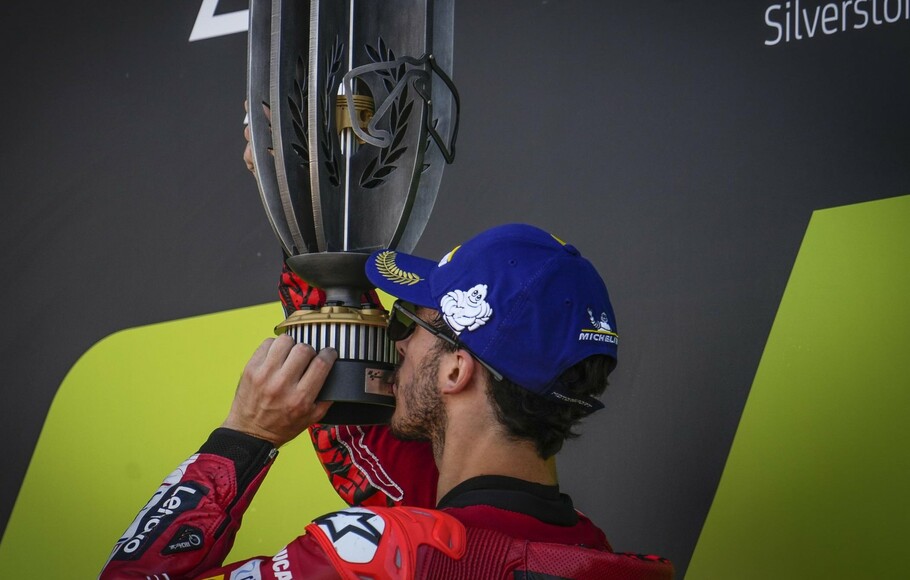 Pembalap Ducati Fransesco Bagnaia mencium trofi juara Grand Prix Inggris di Sirkuit Silverstone. 7 Agustus 2022.