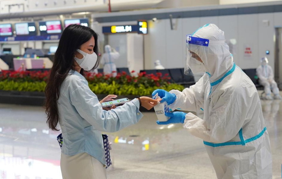 Seorang anggota staf mendisinfeksi tangan seorang penumpang di Bandara Internasional Haikou Meilan di Haikou, Provinsi Hainan, Tiongkok selatan, Kamis 11 Agustus 2022.