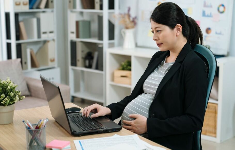 Ilustrasi karyawan hamil sedang bekerja di kantor.