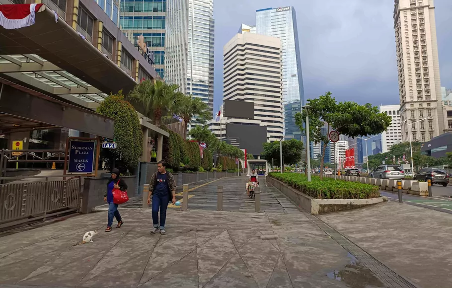Pejalan kaki melintas di trotoar Jalan Jenderal Sudirman, di Jakarta.