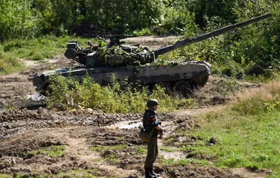 Seorang tentara melihat satu tank yang mengambil bagian dalam latihan militer di tempat pelatihan Uspenovskyi di luar kota Yuzhno-Sakhalinsk di Timur Jauh Rusia pada Minggu 4 September 2022. 