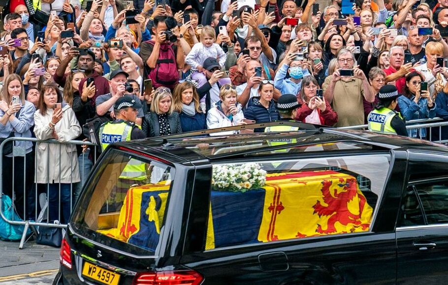 Anggota masyarakat berkumpul untuk menyaksikan mobil jenazah yang membawa peti mati Ratu Elizabeth II, terbungkus Royal Standard of Scotland, saat didorong melalui Edinburgh menuju Istana Holyroodhouse, pada Minggu 11 September 2022.