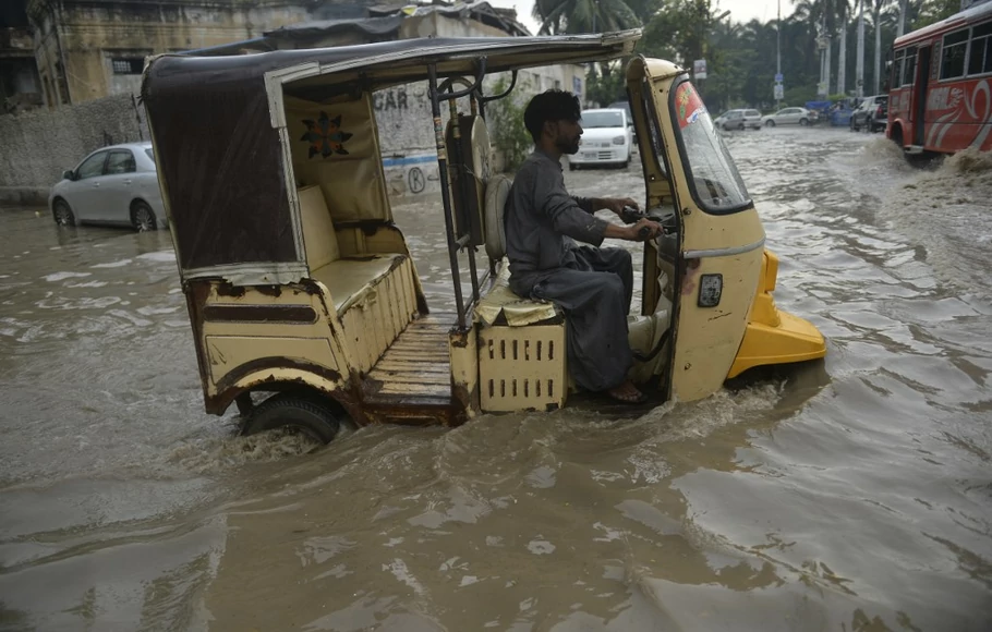 Bajaj mencoba melewati jalan yang banjir setelah hujan lebat di Karachi pada 13 September 2022.
