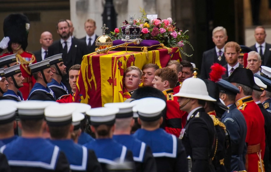 Satu kelompok pengawal Grenadier Batalyon 1 menempatkan peti mati Ratu Elizabeth II, terbungkus Royal Standard, ke dalam Kereta Senjata Angkatan Laut Kerajaan di luar Westminster Hall, di Istana Westminster di London pada Senin 19 September 2022. 