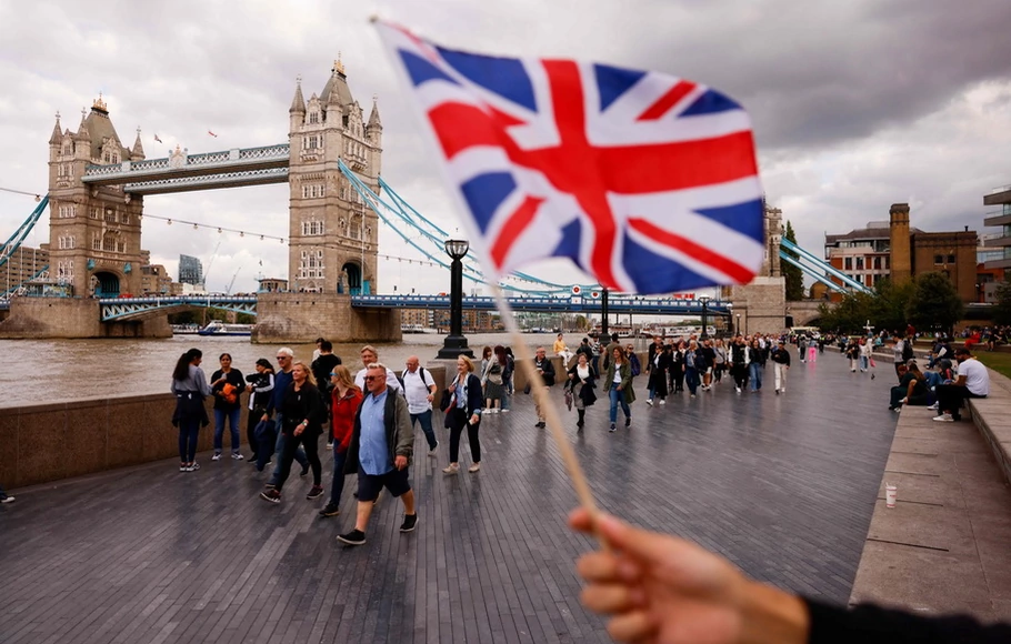 Seseorang mengibarkan bendera Union Jack sebagai anggota antrean publik di South Bank of the River Thames, di samping Tower Bridge, saat mereka mengantre untuk memberi penghormatan kepada mendiang Ratu Elizabeth II, di London pada Kamis 15 September 2022.