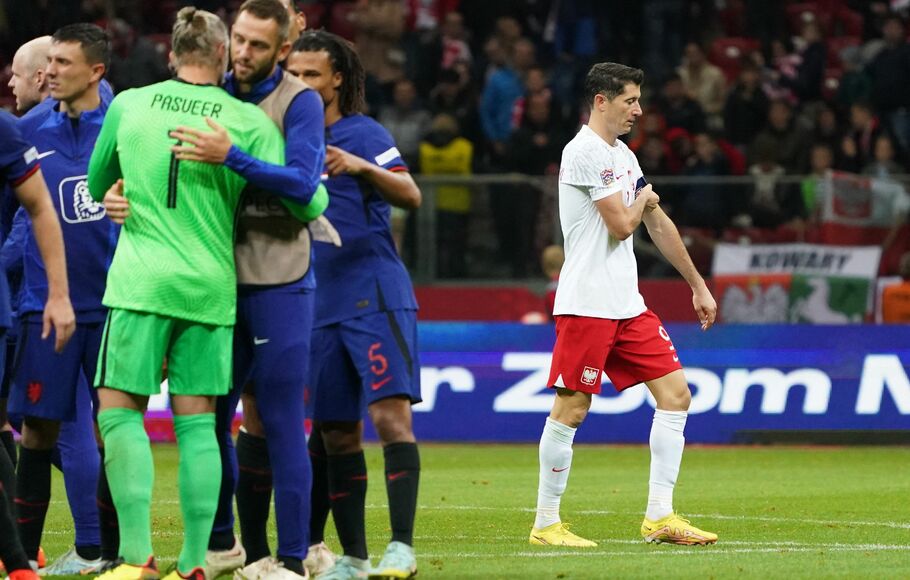 Para pemain Belanda merayakan kemenangan, sedangkan terlihat striker Polandia Robert Lewandowski kecewa.