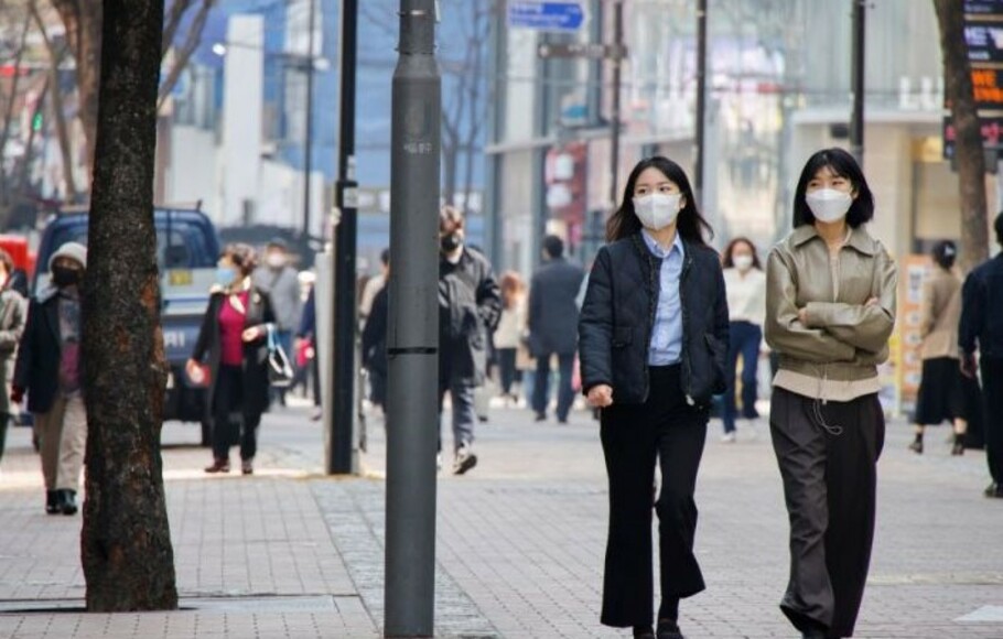 Warga memakai masker berjalan di distrik perbelanjaan di tengah pandemi Covid-19 di Seoul, Korea Selatan.