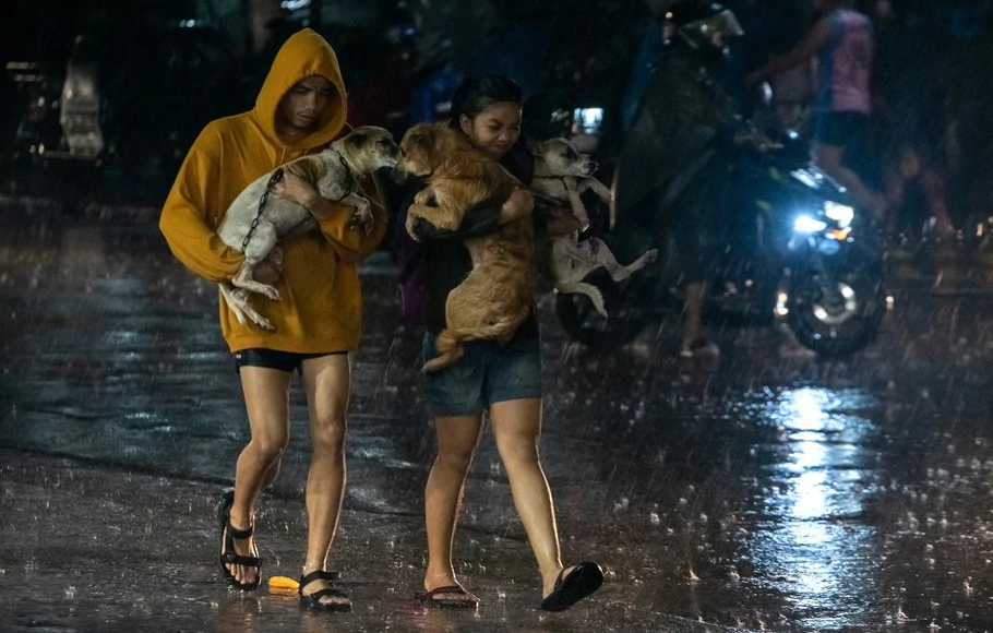 Foto yang diambil pada 25 September 2022 menunjukkan, warga membawa hewan peliharaan mereka ke pusat evakuasi di tengah hujan lebat yang dibawa oleh Topan Super Noru di kota Marikina, pinggiran kota Manila.