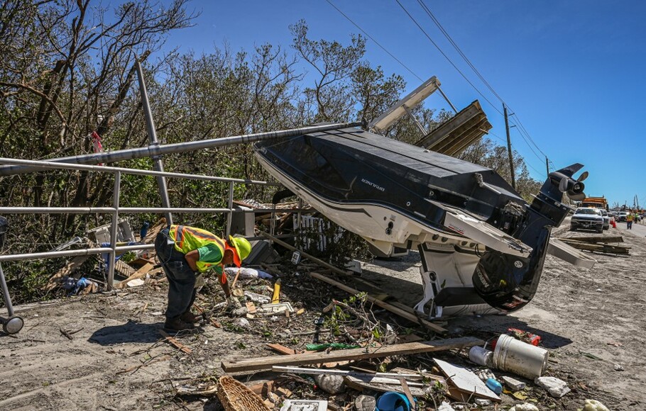 Pekerja Departemen Perhubungan Florida membersihkan puing-puing di Pantai Fort Myers setelah dihantam Badai Ian pada 30 September 2022.