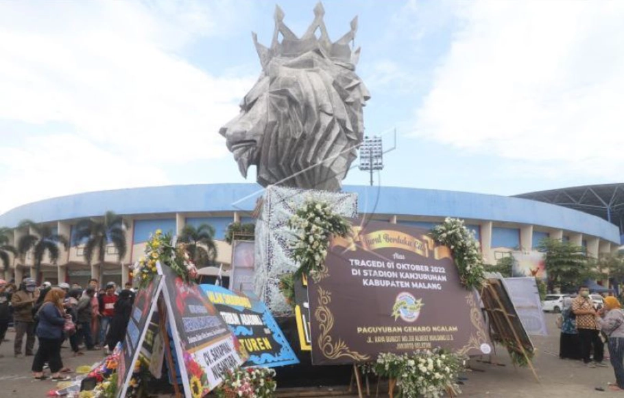 Warga berdoa di patung Singa Tegar kawasan Stadion Kanjuruhan yang dipenuhi karangan bunga di Malang, Jawa Timur, Senin, 3 Oktober 2022.