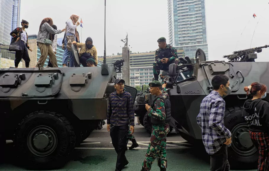 Sejumlah warga bersama prajurit TNI manaiki kendaraan tempur saat pawai alutsista usai upacara peringatan HUT ke-77 TNI di kawasan Bunderan HI, Jakarta, Rabu 5 Oktober 2022.