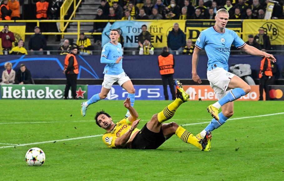 Striker Manchester City, Erling Haaland (kanan) dan bek Dortmund Mats Hummels  berjibaku memperebutkan bola dalam laga Liga Champions di Dortmund, Rabu, 26 Oktober 2022.