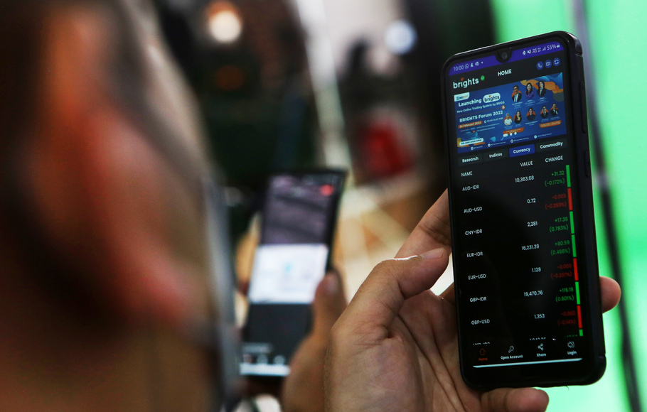 Investor melihat pergerakan saham menggunakan telepon seluler.