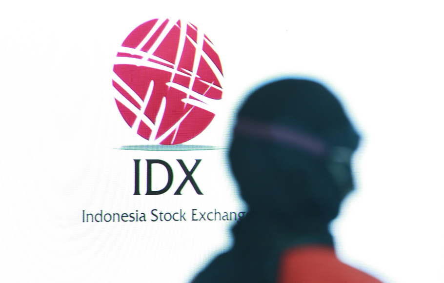 Karyawan melintas di depan monitor logo IDX di Bursa Efek Indonesia (BEI), Jakarta.