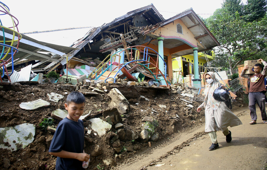 Sejumlah warga melewati reruntuhan rumah di Desa Sukamulya, Kecamatan Cugenang Kabupaten Cianjur, Rabu 23 November 2022. 