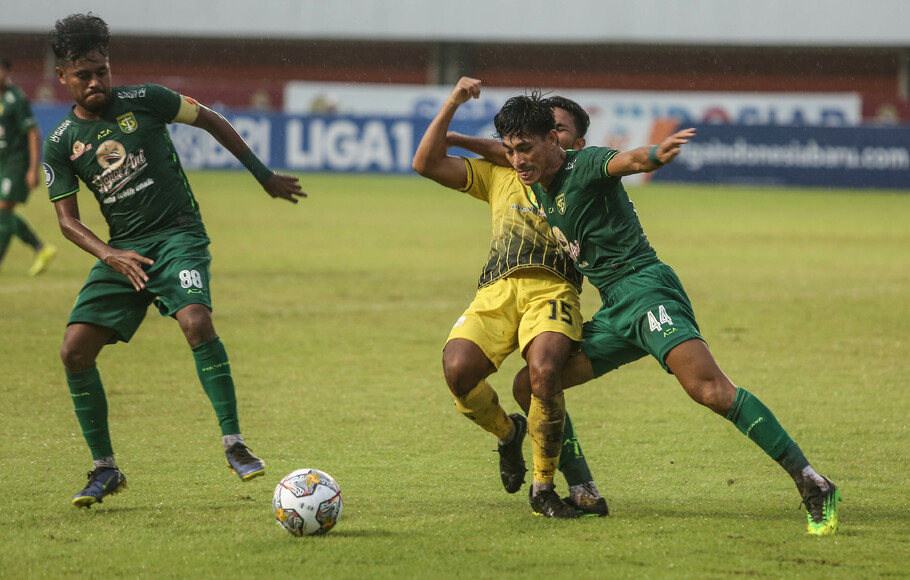 Pemain Persebaya Riswan Lauhin (kanan) berebut bola dengan gelandang Barito Putera Rafi Syalahil (tengah) saat pertandingan Liga 1 di Stadion Maguwoharjo, Sleman, Yogyakarta, Selasa, 6 Desember 2022. Persebaya berhasil mengalahkan Barito Putera dengan skor 3-2. 