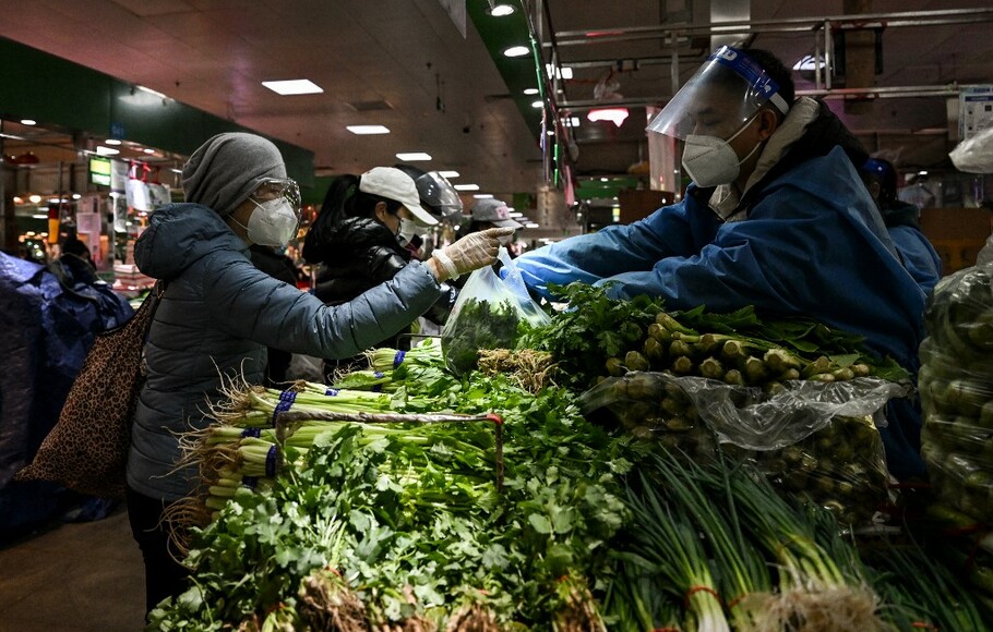 Seorang wanita membeli sayuran di pasar di Beijing pada Kamis 8 Desember 2022.