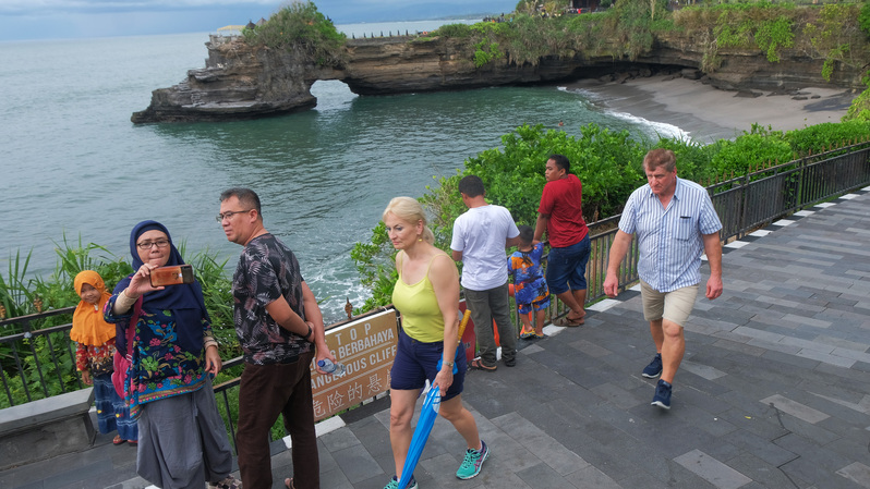 Wisatawan menikmati pemandangan di area objek wisata Tanah Lot, Tabanan, Bali, Minggu (16/2/2020). Dinas Pariwisata Bali menaksir kehilangan pendapatan dari pariwisata sekitar Rp 10 miliar dalam waktu hampir sebulan akibat pembatalan kunjungan sekitar 20.000 wisatawan Tiongkok ke Bali karena merebaknya wabah virus korona yang berasal dari Tiongkok.