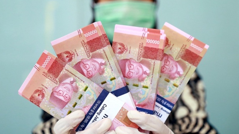 Karyawan memperlihatkan uang rupiah di sebuah penukaran uang di Jakarta, Rabu (29/4/2020). Foto: BeritaSatu Photo/Mohammad Defrizal