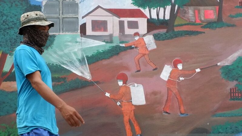 Seorang warga melintas di dekat mural kampanye pencegahan Covid-19 di Depok, Jawa Barat, Kamis (13/8/2020). Kota Depok mulai Senin (31/8/2020) menerapkan aturan jam malam guna meminimalkan risiko penularan Covid-19. (Antara)