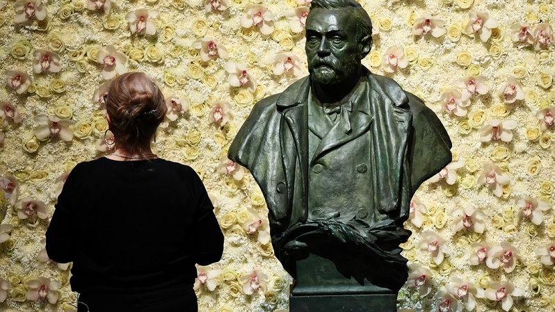 Foto yang diambil pada 10 Desember 2019 memperlihatkan seorang pengunjung berdiri di depan patung pendiri Hadiah Nobel, Alfred Nobel sebelum mengikuti upacara penghargaan di Concert Hall, Stockholm, Swedia. ( Foto: JONATHAN NACKSTRAND / AFP )