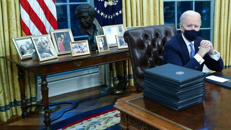 Presiden Amerika Serikat (AS) Joe Biden menandatangani perintah eksekutif di Meja Resolute, Ruang Oval, pada 20 Januari 2021. ( Foto: REUTERS/Tom Brenner )