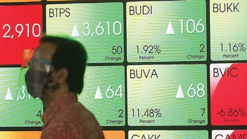Pekerja melintasi monitor saham di gedung BEI, Jakarta, belum lama ini. Foto ilustrasi: Investor Daily/David Gita Roza