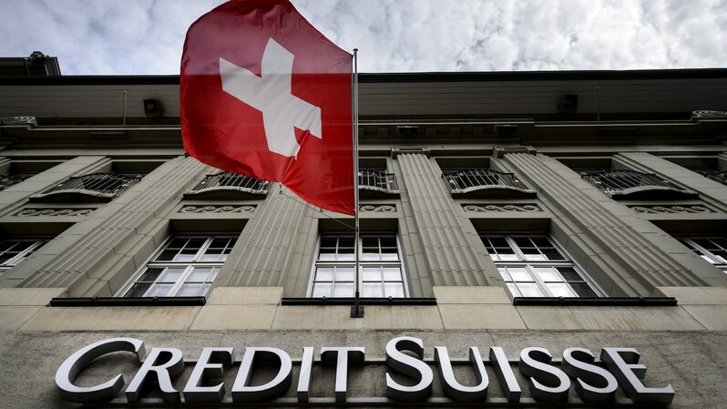Bendera nasional Swiss berkibar di atas plang nama gedung Credit Suisse di Bern, Swiss. (Foto: FABRIC COFFRINI / AFP / Getty Images)
