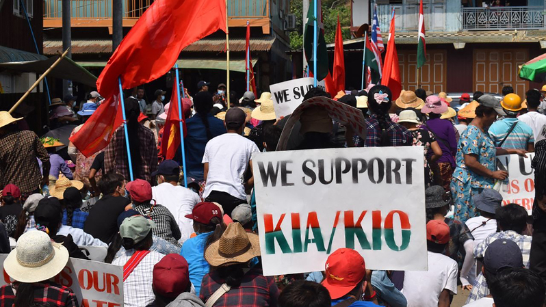 Seorang pengunjuk rasa memegang plakat mendukung Tentara Kemerdekaan Kachin (KIA) dan Organisasi Kemerdekaan Kachin (KIO) selama aksi demonstrasi menentang kudeta militer di Hpakant, di negara bagian Kachin, Myanmar, pada 3 Mei 2021 .  Foto ilustrasi: HANDOUT / KACHINWAVES / AFP 
