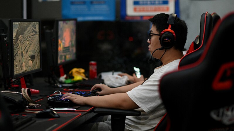 Seorang pria tengah bermain game online di sebuah toko komputer di Beijing, Tiongkok pada 31 Agustus 2021. ( Foto: NOEL CELIS  / AFP )