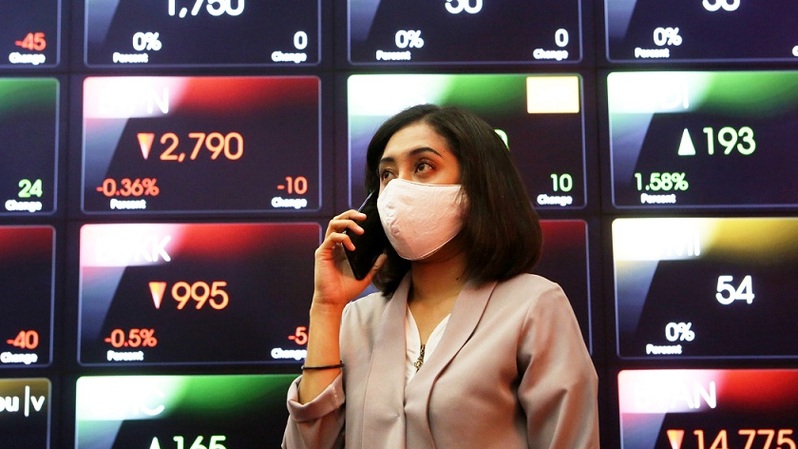 Karyawan sedang menggunakan ponsel dengan latar belakang monitor saham di Bursa Efek Indonesia, Jakarta. Foto ilustrasi: Beritasatu Photo/Uthan AR