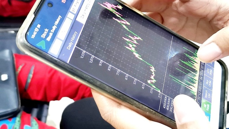 Investor memantau pergerakan harga saham melalui smartphone. Foto ilustrasi:  Investor Daiky/David Gita Roza 
