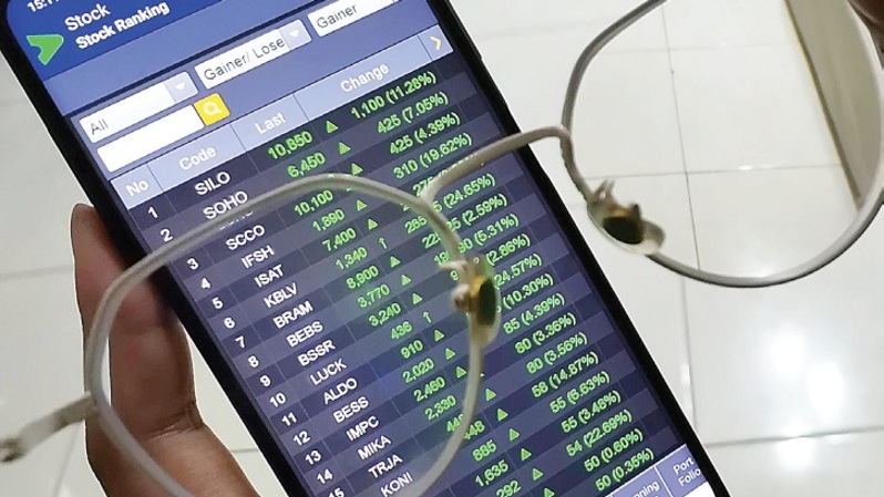 Investor memantau pergerakan saham melalui layar ponsel. Foto ilustrasi: Investor Daily/David Gita Roza
