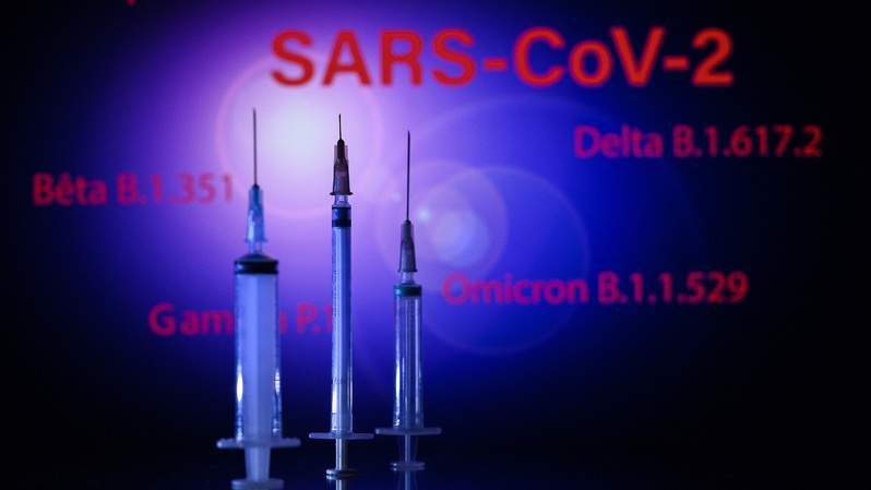 Ilustrasi jarum suntik dengan latar belakang varian-varian virus SARS-Cov-2, yang terdiri atas Alpha, Beta, Delta, Gamma dan Omicron.  Foto ilustrasi: Lionel Bonaventure / AFP 