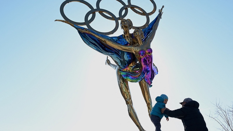 Seorang anak berdiri di atas patung yang mengusung Cincin Olimpiade berjudul 