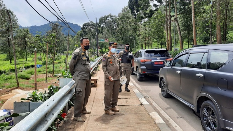 Petugas Satpol PP menggunakan pengeras suara membubarkan kerumunan di area kebun teh, Puncak, Bogor, Sabtu (1/1/2022). 